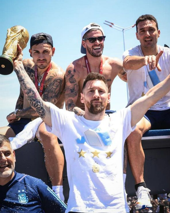 Leo Messi tiene la coppa del mondo e altri calciatori festeggiano con lui