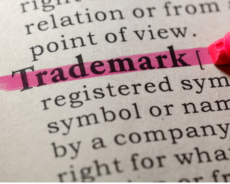 Evidenziatore rosa sottolinea la parola trademark/marchio su un dizionario